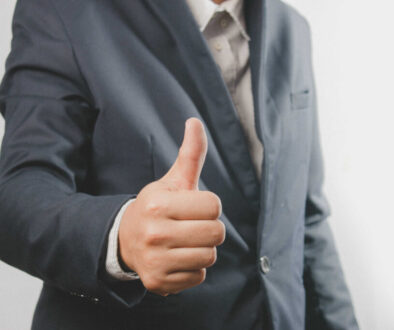Close up of a businessman in a suit with a thumb up standing. Do