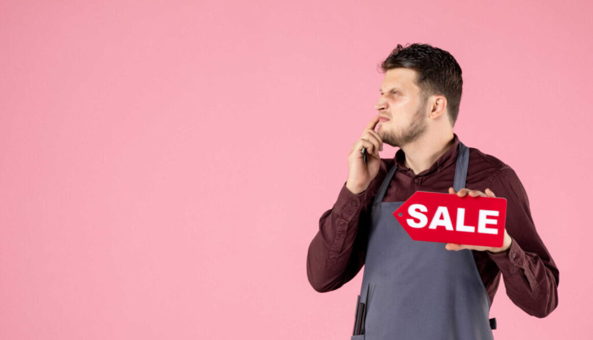 front-view-male-hairdresser-with-sale-nameplate-scissors-pink-background