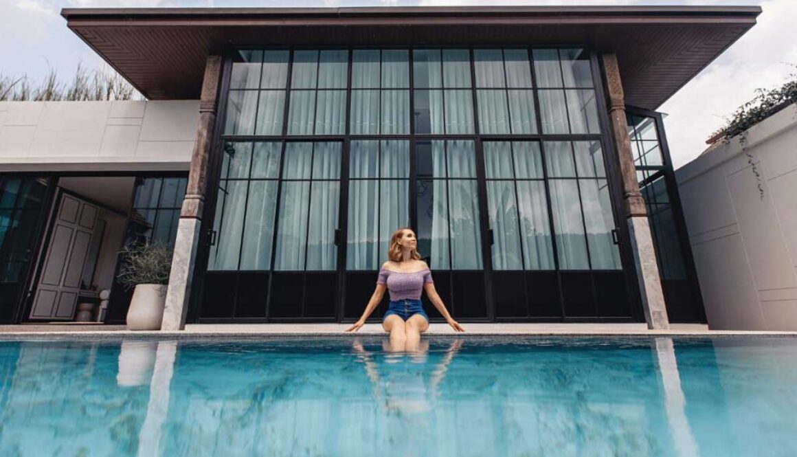 adorable-lovely-young-model-wearing-colored-jacket-shorts-is-sitting-by-pool-with-clear-water-against-background-large-house-rich-life-concept_0x800