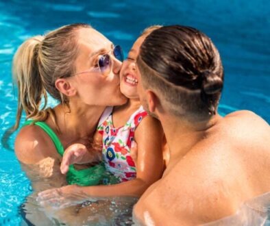 happy-parents-kissing-their-smiling-daughter-while-swimming-pool_0x800