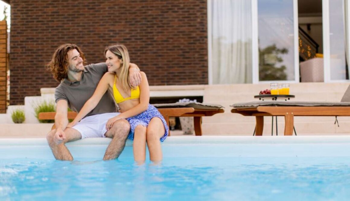 young-couple-relaxing-by-swimming-pool-house-backyard_0x800